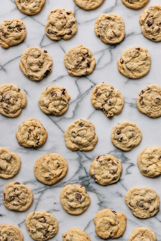 Rows of chocolate chip cookies laid out on white marble