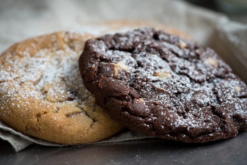 A dark chocolate cookie next to a vanilla one, both dusted with sugar (stock photo)