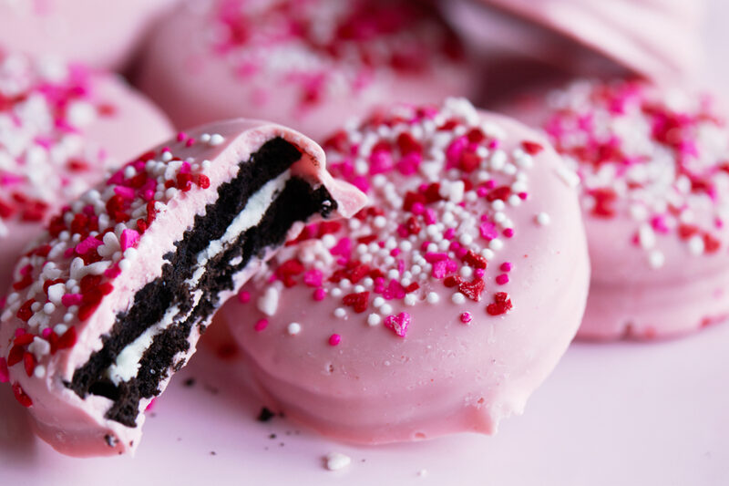 Pink-coated sandwich cookies covered in sprinkles