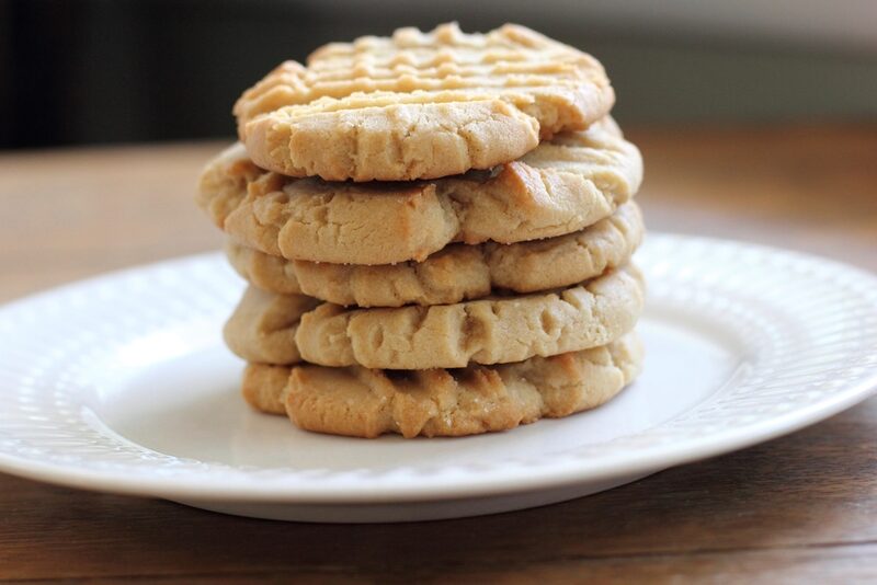 A tall stack of golden cookies on a white plate